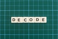 Decode word made of square letter word on green square mat background