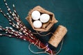 Decor for Easter holidays, a willow branch and decorative colored eggs in burlap on a concrete blue background, top view Royalty Free Stock Photo