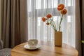 Decor elements of the guest room and rest room with a tea table, an armchair and a bouquet of flowers and a cup of coffee Royalty Free Stock Photo