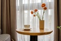 Decor elements of the guest room and rest room with a tea table, an armchair and a bouquet of flowers and a cup of coffee Royalty Free Stock Photo