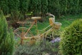 The decor of an old brown metal bike stands in the green grass and coniferous bushes