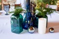 The decor of the table in the restaurant.Bottles of green and blue glass, mirror balls and spruce paws.