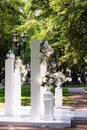 decor of wedding celebration in nature, white columns with vases with flowers, side view, lush white flowers in vases stand