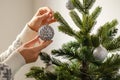 Winter holidays and people concept - close up of young woman hand decorating christmas tree with ball