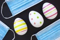 Decorate Easter eggs with surgical face masks around on a black background. Royalty Free Stock Photo