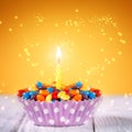 Decorated Birthday cupcake with one lit candle and Royalty Free Stock Photo