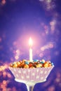Decorated Birthday cupcake with one lit candle and colorful candies on yellow background. Holidays greeting card Royalty Free Stock Photo