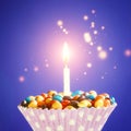 Decorated Birthday cupcake with one lit candle and colorful candies on yellow background. Holidays greeting card Royalty Free Stock Photo