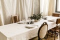 Decorated boho table. The table is covered with a tablecloth, plates, glasses and a vase with a green plant