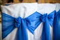 Decorated chairs with black fabric and big blue satin bows. Silk bow tied on back of chair in party at restaurant. Dark cloth Royalty Free Stock Photo