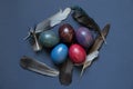 decorated chicken eggs with watercolor multi-colored paints and dove feathers on a blue background, easter prazdnik