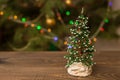 Decorated Christmas small tree on wooden table with glowing background