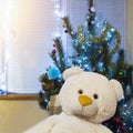 Decorated Christmas tree and big teddy bear. Cute New Year present under shining pine