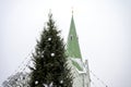 Decorated Christmas tree and church bell tower isolated on sky background, Dobele, Latvia Royalty Free Stock Photo