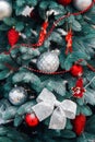 Decorated Christmas tree closeup. Red and golden balls and illuminated garland with flashlights. New Year baubles macro