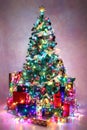 Decorated Christmas tree with colorful lights surrounded by pres Royalty Free Stock Photo