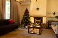 Decorated christmas tree by fireplace in homely living room, copy space Royalty Free Stock Photo