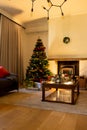 Decorated christmas tree by fireplace in homely living room, copy space Royalty Free Stock Photo