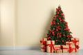 Decorated Christmas tree and gift boxes near beige wall Royalty Free Stock Photo