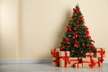 Decorated Christmas tree and gift boxes near beige wall Royalty Free Stock Photo