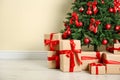 Decorated Christmas tree and gift boxes near wall. Space for text Royalty Free Stock Photo