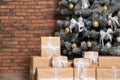 Decorated Christmas tree and gift boxes near wall. Space for text Royalty Free Stock Photo