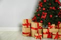 Decorated Christmas tree and gift boxes near light wall Royalty Free Stock Photo