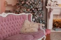 Decorated Christmas tree with gifts, fireplace and garland. interior living room with pink sofa and white fireplace on christmas. Royalty Free Stock Photo