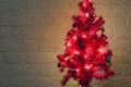 Decorated christmas tree with lighted lights isolated on a white brick wall background Royalty Free Stock Photo