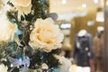 Decorated Christmas tree luxury pastel flowers on blurred shopwindow in mall interiors. Xmas background.