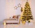 Decorated Christmas tree with party lights and snowflakes and icicle shape ornaments  beige canape sofa. Royalty Free Stock Photo