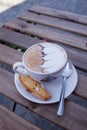 Decorated coffee with cookie and spoon on a wooden table. Close Royalty Free Stock Photo