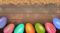 Decorated colorful Easter eggs on background with wooden texture and with sugar balls powder. Top view with copy space.