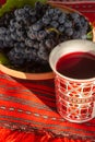 Decorated cup with red stum and grapes near in a clay bowl Royalty Free Stock Photo