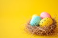 Decorated Easter eggs in nest on yellow background, top view. Composition with empty place for text Royalty Free Stock Photo