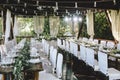 Decorated elegant wooden wedding table for banquet outdoor in garden gazebo with lamp, in the style of rustic with eucalyptus and Royalty Free Stock Photo