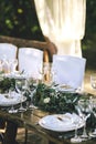 Decorated elegant wooden wedding table in rustic style with eucalyptus and flowers, porcelain plates, glasses and chairs Royalty Free Stock Photo