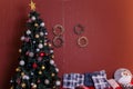 Decorated fir-tree with star on top, golden wreath on wall, striped pillows on sofa, copy space. Winter holidays, Merry Christmas