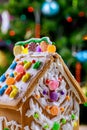 Decorated gingerbread house in front of a Christmas tree Royalty Free Stock Photo