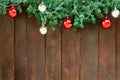 Decorated green Christmas tree branch by colorful (red and silver) bauble ball and light on top of aged brown wood wall Royalty Free Stock Photo