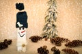 Decorated handmade wooden snowman with pine cones on the snowy background