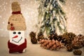 Decorated handmade wooden snowman with pine cones on the snowy background