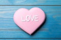 Decorated heart shaped cookie with word Love on blue wooden table, top view. Valentine`s day treat Royalty Free Stock Photo