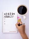 Decorated notebook for writing New Year's resolutions on a table with a coffee cup on the side and a hand writing Royalty Free Stock Photo