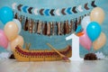 Decorated photo zone for 1 year Indian Apache chief with a canoe for a children`s party. First birthday and smash cake