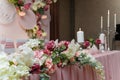 Decorated pink wedding presidium, festive arch, screen for just married, event organization. Beautiful flowers, leaves, candles.