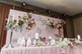 Decorated pink wedding presidium, festive table and arch for just married, event organization. Beautiful flowers and burning