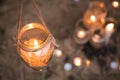 Decorated romantic place for a date with jars full of candles hunging on tree and standing on a sand. Copy Space