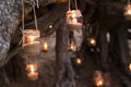 Decorated romantic place for a date with jars full of candles hunging on tree and standing on a sand. Copy Space