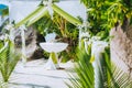 Decorated romantic wedding celebration location, table and chairs on tropical beach. Lush green foliage and white lowers Royalty Free Stock Photo